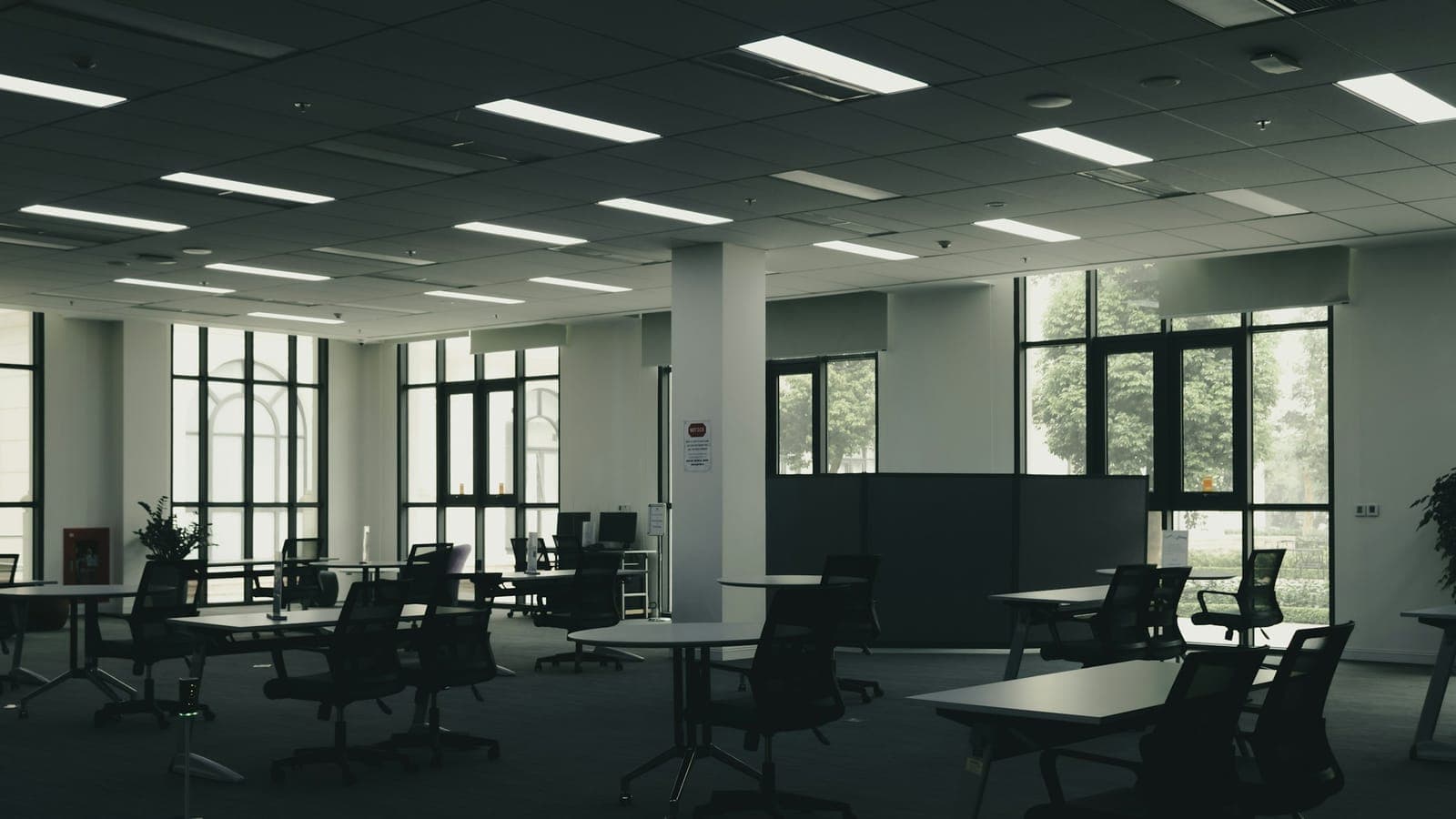 Oficina diáfana y vacía con mesas y sillas, en penumbra